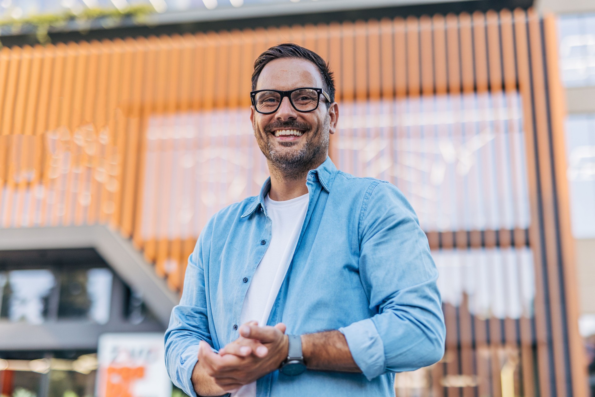 Portrait of a handsome, cheerful, smiling man with modern buildings in the background.